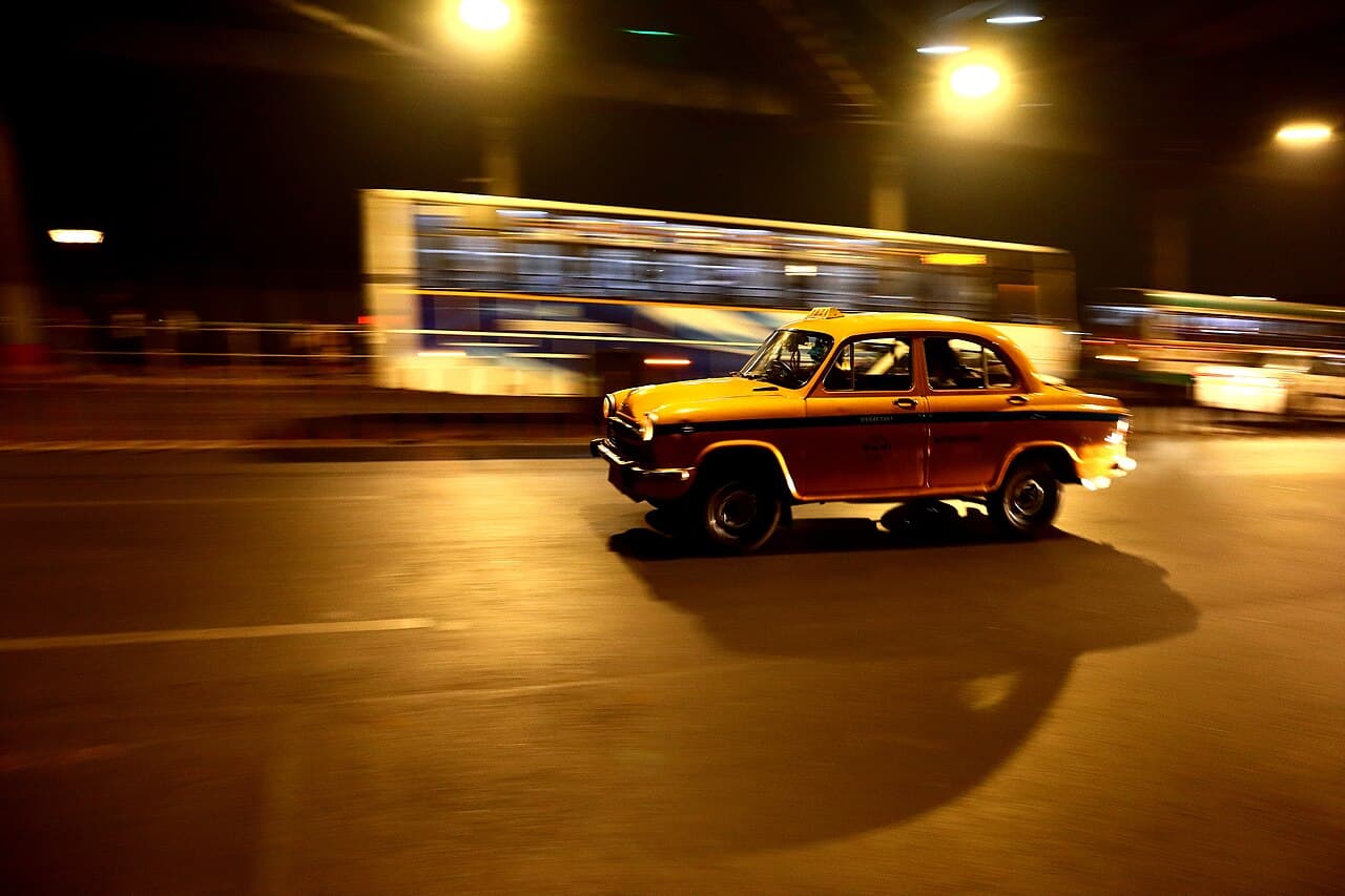 A yellow taxi speeding through Kolkata at night